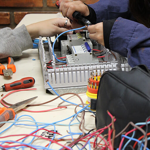 Plano detalle de dos jóvenes armando un panel eléctrico complejo